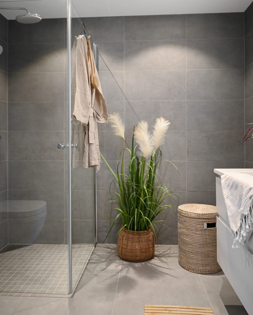 Lys grått baderom med mosaikk i dusjsone